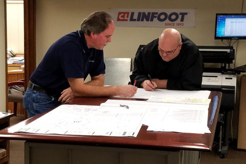 Engineers and estimators leaning over plans in discussion working